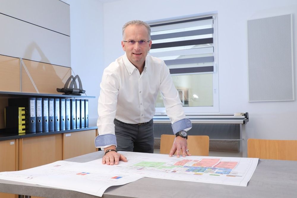 Michael Kolar steht an einem Tisch auf dem Skizzen liegen.